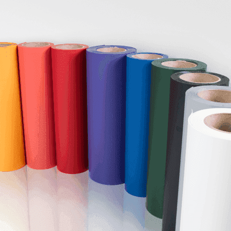 Colorful rolls of vinyl or adhesive film in a row, including yellow, orange, red, purple, blue, green, black, gray, and white, standing vertically against a white background.